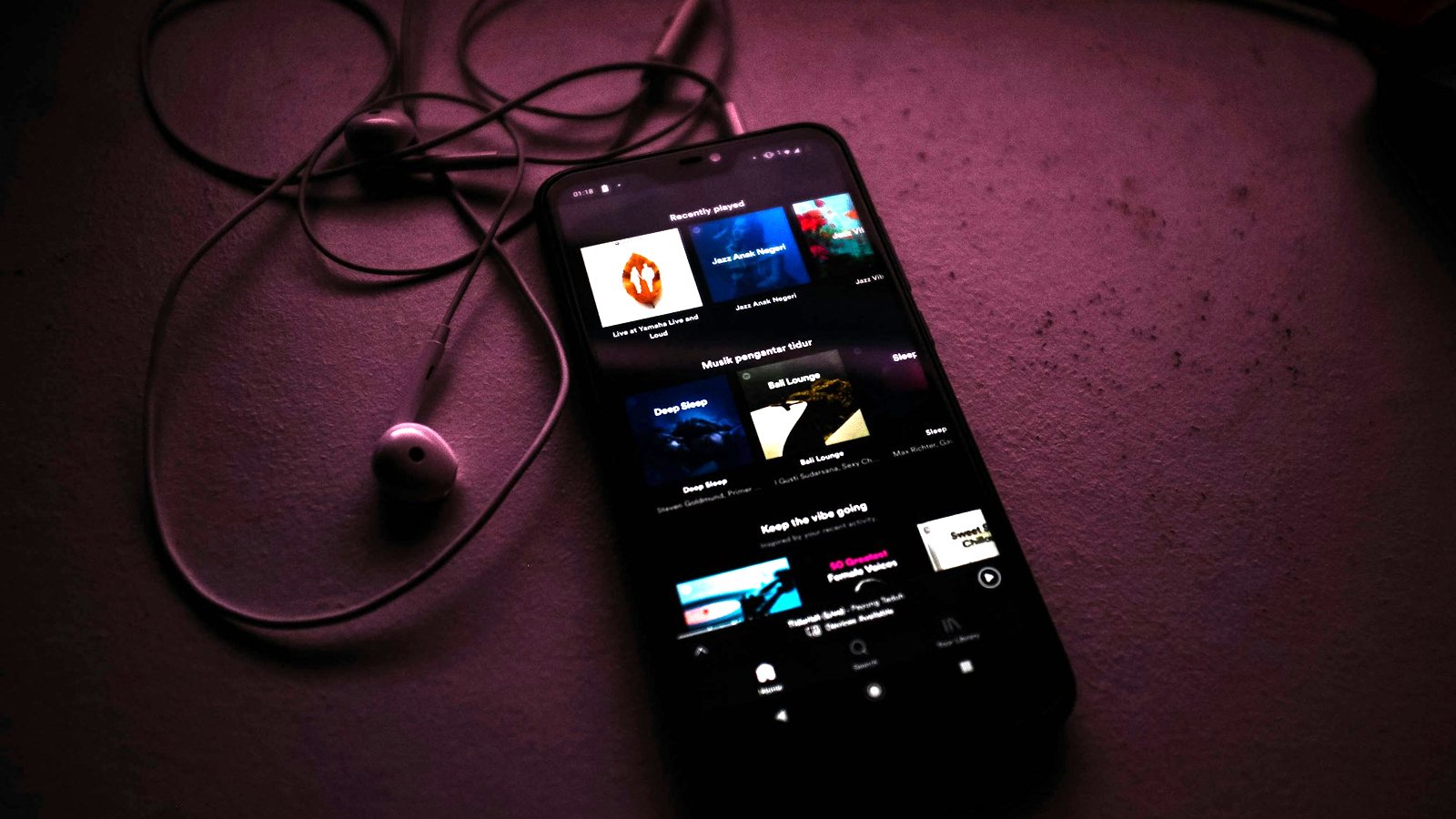Smartphone with a music streaming app open next to earphones